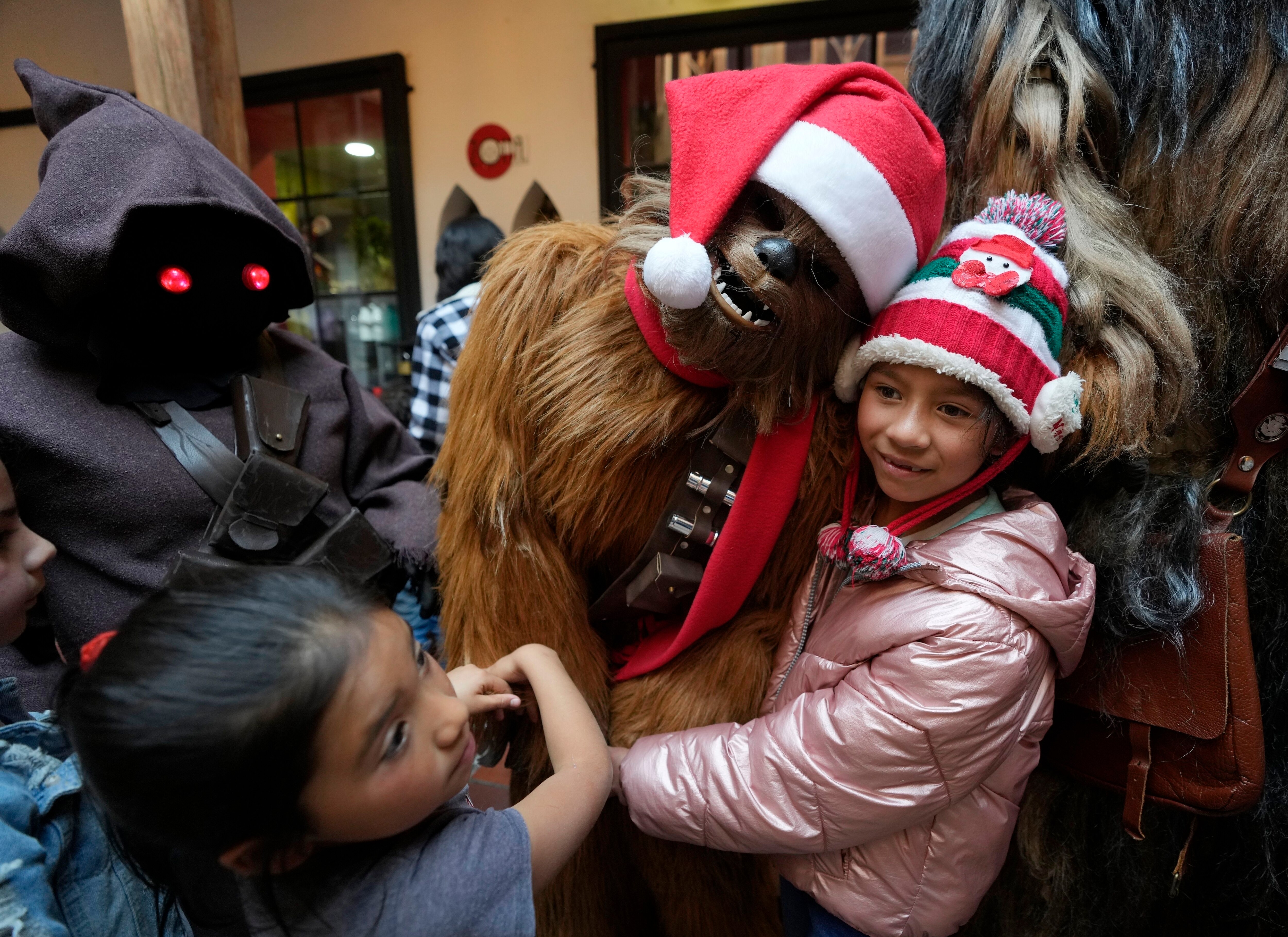 Un wookie de Star Wars posa para la foto con una niña durante un evento solidario organizado por la fundación "Vida Nueva" que trabaja para ayudar a extrabajadoras sexuales y víctimas de violencia, en Bogotá, Colombia, el jueves 22 de diciembre de 2022. (AP Foto/Fernando Vergara)