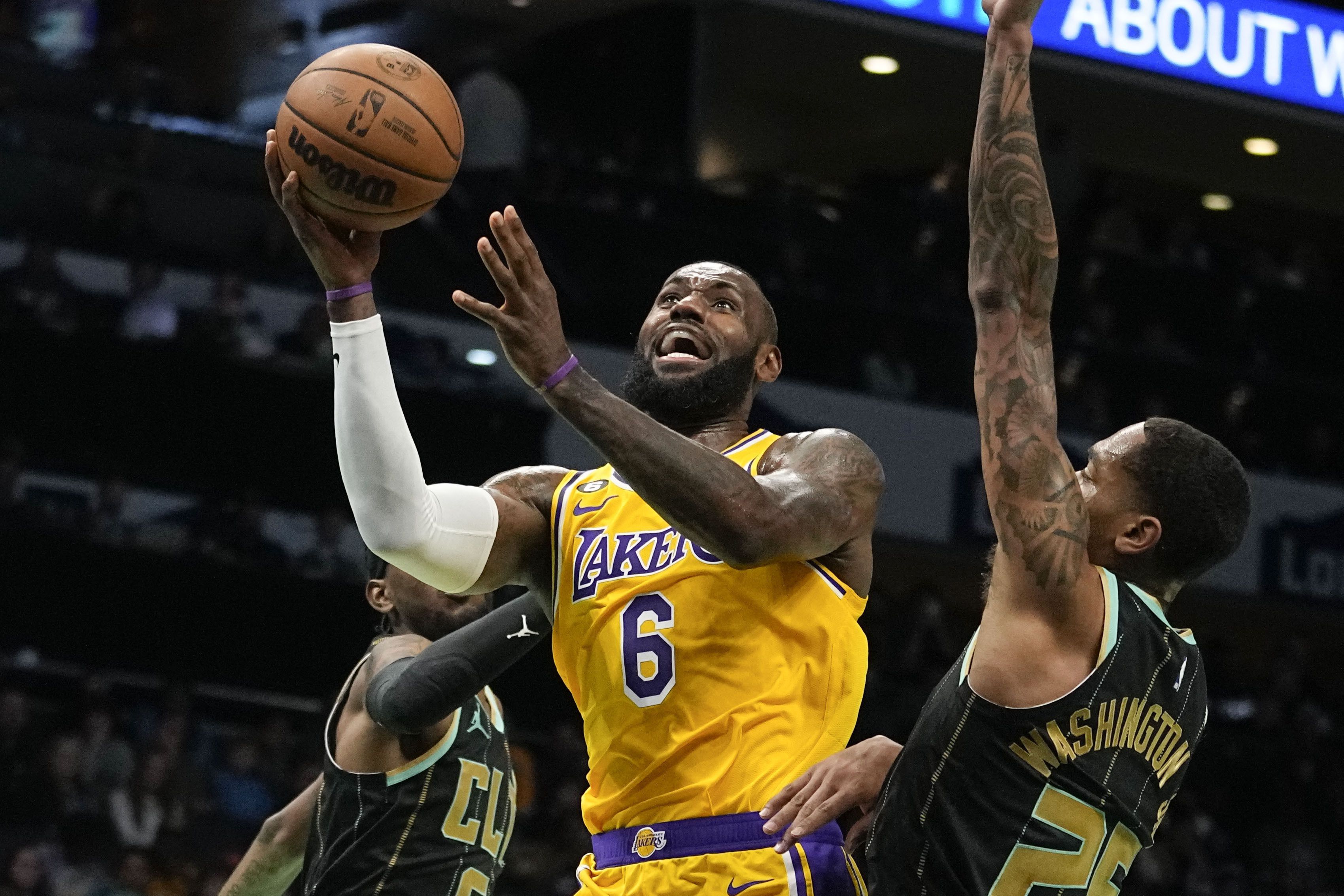 El alero de los Lakers de Los Ángeles LeBron James lanza el balón entre los delanteros Jalen McDaniels y P.J. Washington de los Hornets de Charlotte en el encuentro del lunes 2 de enero del 2023. (AP Foto/Chris Carlson)